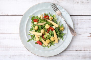 Tasty baby corn with vegetables, arugula and mushrooms on white wooden table, top view
