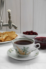 Cup of aromatic tea and treats on table