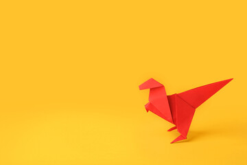 Origami art. Handmade red paper dinosaur on yellow background, space for text