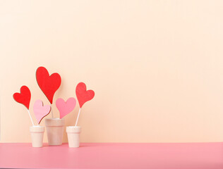 Fototapeta na wymiar Valentines hearts in a plant pot with beige background