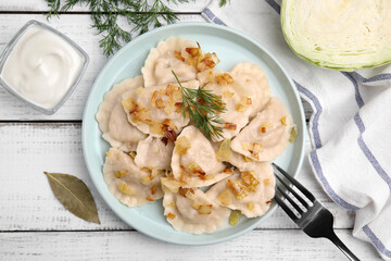 Cooked dumplings (varenyky) with tasty filling, fried onions and dill on wooden table, flat lay