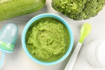 Healthy baby food. Bowl with delicious broccoli puree and ingredients on white wooden table, flat lay