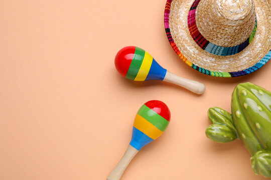 Colorful maracas, toy cactus and sombrero hat on beige background, flat lay with space for text. Musical instrument