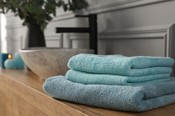 Obraz na płótnie Canvas Folded towels near stylish vessel sink on bathroom vanity, space for text. Interior design