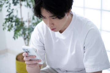 スマホを見て驚くイケメンの男性