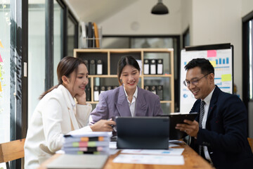 Group of young Asian business people brainstorming, looking at laptop computer