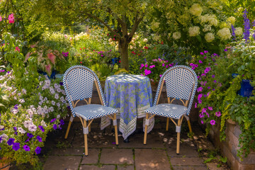 Awash with color this vibrant terrace garden, lush green foliage, chartreuse and violet blooms create a romantic, European feel along with French blue tableclothed bistro table and chairs. 