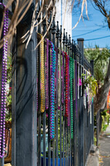 Colorful Mardi Gras beads hanging on iron fencing background