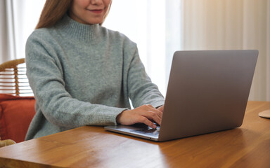 Closeup image of a young woman working on laptop computer at home