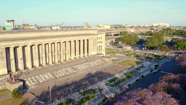 Aerial orbit of the UBA Law School with a protest writing on the stairs "Transfeminist Judicial Reform" at sunset in a touristic area of Retiro neighborhood.
