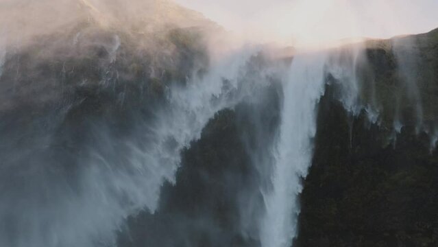 Mist blows over top of cliff, close up of Iceland reverse waterfall.