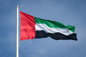 Naklejka na ściany i meble The flag of the United Arab Emirates atop Abu Dhabi's giant flag pole, one of the highest in the world.
