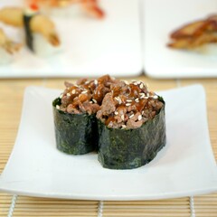 two pieces of bulgogi sushi rolled with seaweed in a white plate
