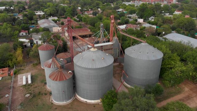 Aerial. Grain silos storage tank, town in Argentina. High angle, approaching shot.
