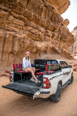 kobieta siedząca na pace samochodu terenowego na pustyni