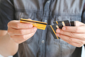 Man holding several credit cards and he is choosing a credit card to pay and spend Payment for goods via credit card. Finance and banking concept.