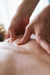 Close up of hands doing shiatsu massage on female back. Health, body care, medicine concept. Copy space. Vertical.