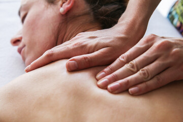 Relaxed female client with closed eyes getting a soft massage on her back. Body care, massage, spa concept.