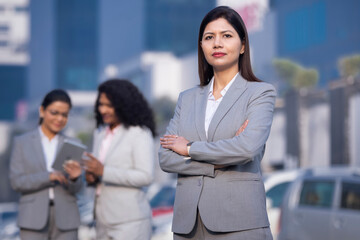 Powerful indian businesswoman leader standing with arm crossed in city office building background