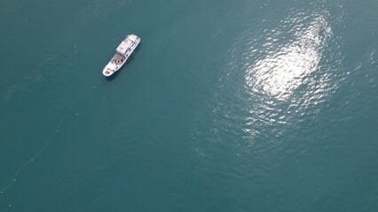 Naklejka premium aerial view of a fishing boat catches fish using nets in the middle of the ocean