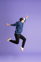 Fototapeta premium image of asian man wearing virtual reality glasses on purple background