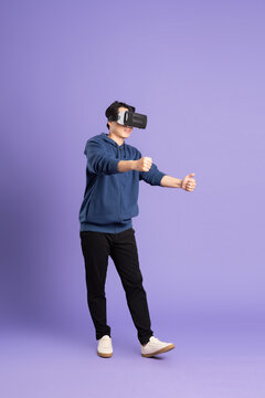 image of asian man wearing virtual reality glasses on purple background
