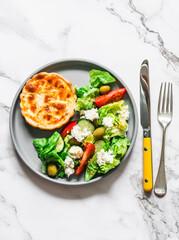 Delicious snack - mini canned tuna, mozzarella quiche and Greek salad on a light background, top view
