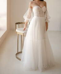 Beautiful brunet bride dressed in the white long wedding dress with the deep neckline. Light chiffon wedding dress with wide collapsible sleeves.