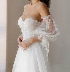 Beautiful brunet bride dressed in the white long wedding dress with the deep neckline. Light...
