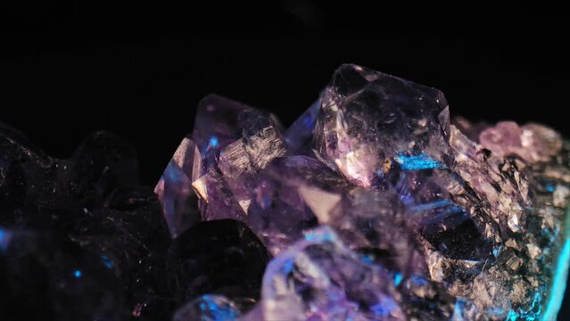 Luminous purple amethyst crystal with color-changing lighting against black background. Smooth panning and macro lens for exquisite details.