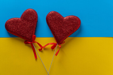 Two red hearts on blue and yellow color paper background for St Valentines day or 14 February, closeup, top view, copy space