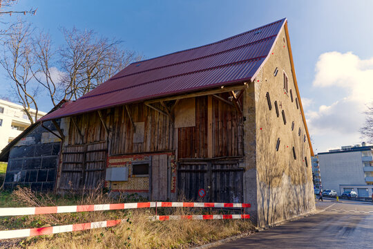 Abandoned weathered old traditional farm building at City of Zürich district Seebach on a blue cloudy winter day. Photo taken January 31st, 2023, Zurich, Switzerland.