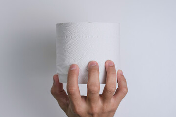 One hand grabbing a roll of toilet paper with isolated white background. Toilet rolls become precious during the coronavirus season.
