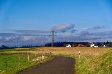 Stubble field at City of Zürich district Seebach on a blue cloudy winter day with pylon of power line in the background. Photo taken January 31st, 2023, Zurich, Switzerland.