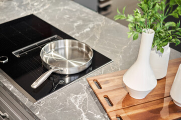 New cookware set on black induction hob in modern kitchen. Pot and frying pan in the kitchen on the...