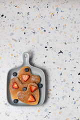 Heart shaped pancakes for romantic breakfast served with strawberry, blueberry and powdered sugar. Valentine's Day concept. Terrazzo background. Top view. Love and hearts theme. Copy space
