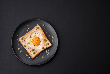 Heart shaped fried egg in bread toast with sesame seeds, flax seeds and pumpkin seeds on a black plate