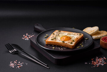 Heart shaped fried egg in bread toast with sesame seeds, flax seeds and pumpkin seeds on a black plate