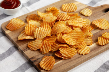 Barbeque Potato Chips on a wooden board, low angle view.