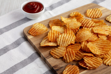 Barbeque Potato Chips on a wooden board, low angle view. Copy space.