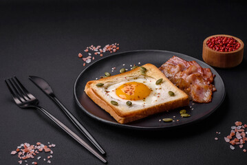 Heart shaped fried egg in bread toast with sesame seeds, flax seeds and pumpkin seeds on a black plate