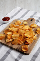 Barbeque Potato Chips on a wooden board, side view.