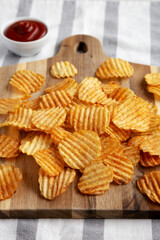 Barbeque Potato Chips on a wooden board, side view.