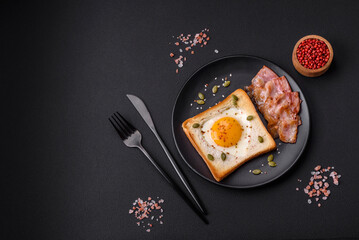 Heart shaped fried egg in bread toast with sesame seeds, flax seeds and pumpkin seeds on a black plate
