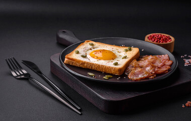 Heart shaped fried egg in bread toast with sesame seeds, flax seeds and pumpkin seeds on a black plate
