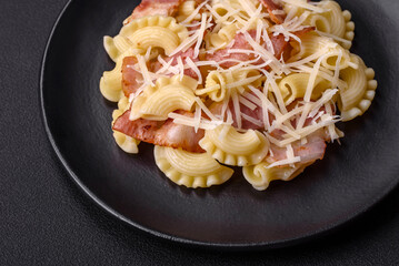 Delicious pasta with bacon and parmesan cheese on a black ceramic plate