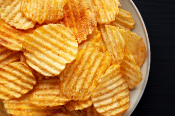 Barbeque Potato Chips on a plate on a black background, top view. Flat lay, overhead, from above.