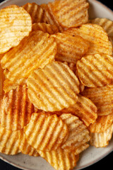 Barbeque Potato Chips on a plate on a black background, top view. Flat lay, overhead, from above.