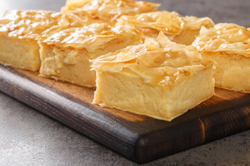 Delicious Greek sweet pastry Galaktoboureko, made of semolina custard in filo closeup on the wooden...