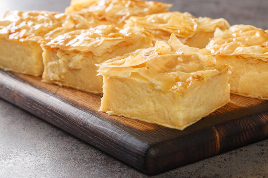 Delicious Greek sweet pastry Galaktoboureko, made of semolina custard in filo closeup on the wooden board on the table. Horizontal